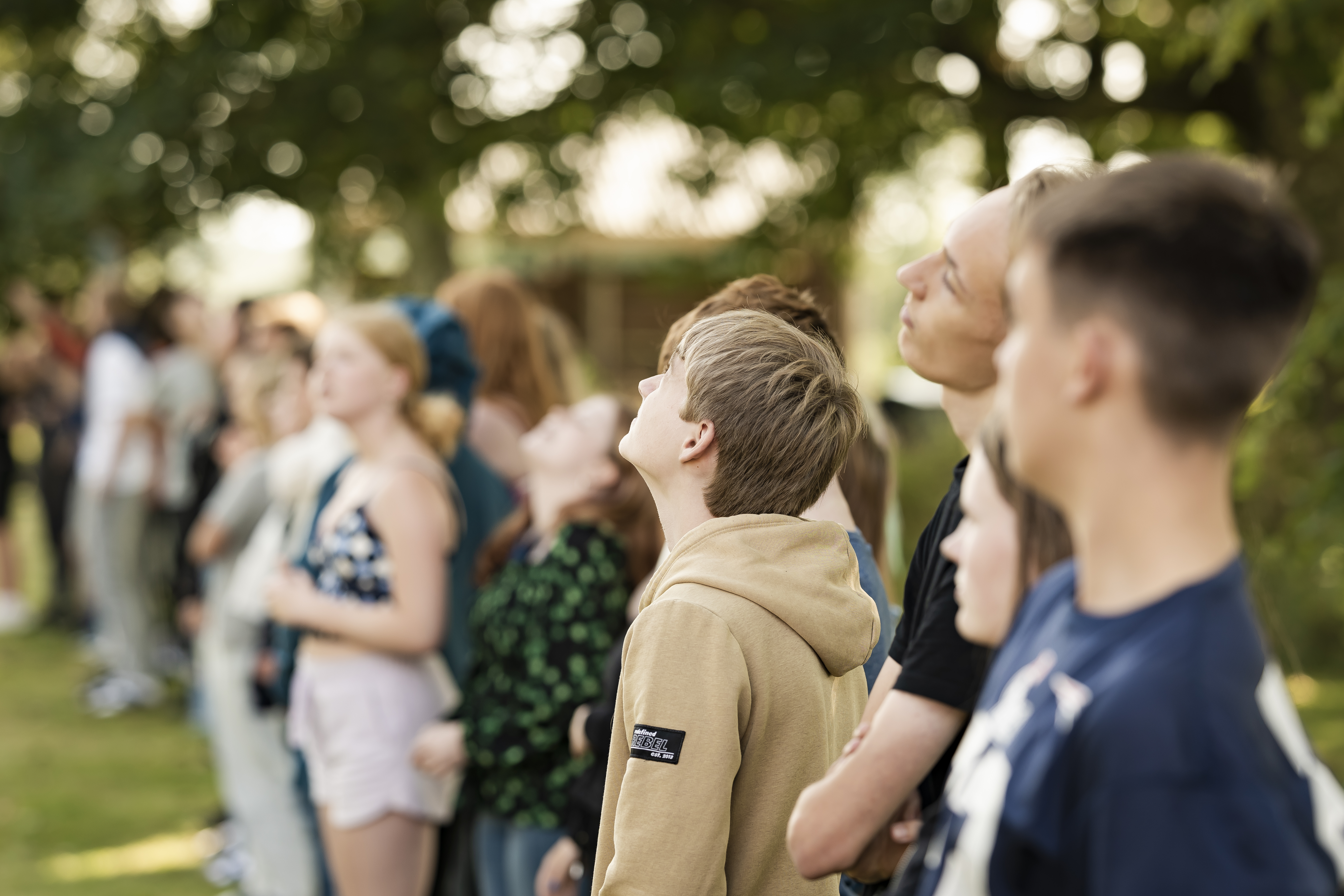 Elever kigger opad under udendørs arrangement på skolens græsplæne