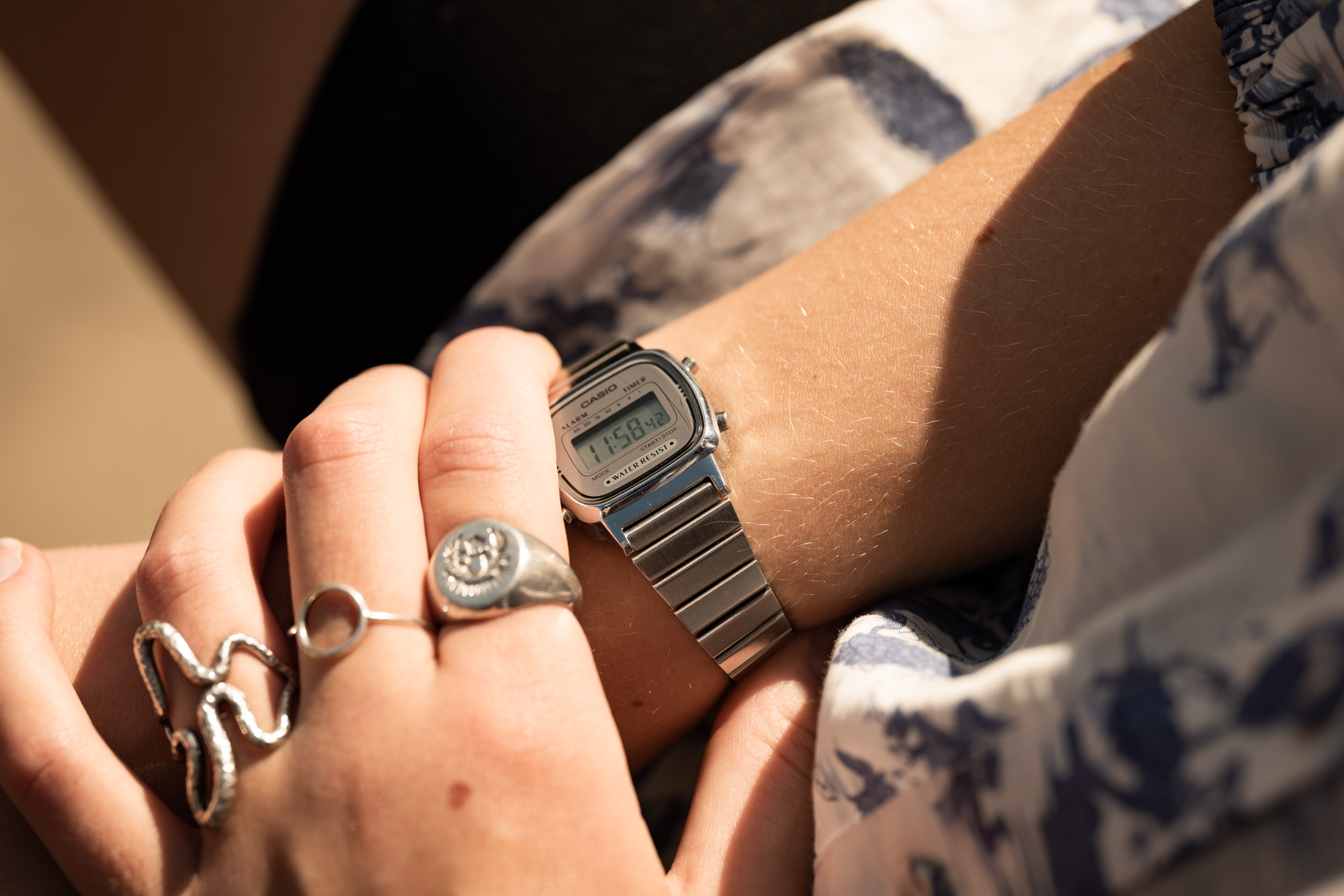 Ung person med digital armbåndsur og sølvringe i sollys