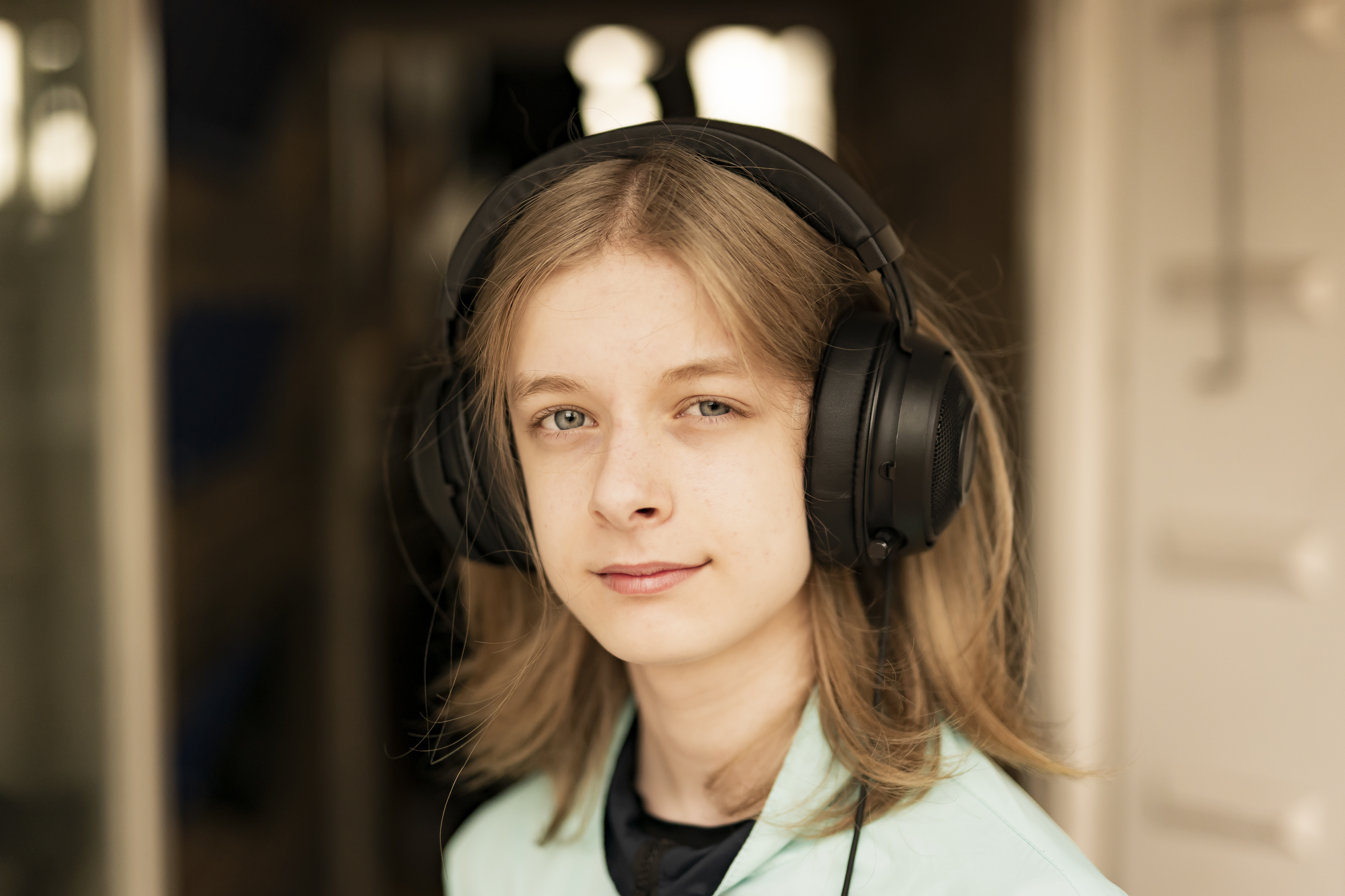 Ung kvinde med lysebrunt hår og hovedtelefoner smiler til kameraet