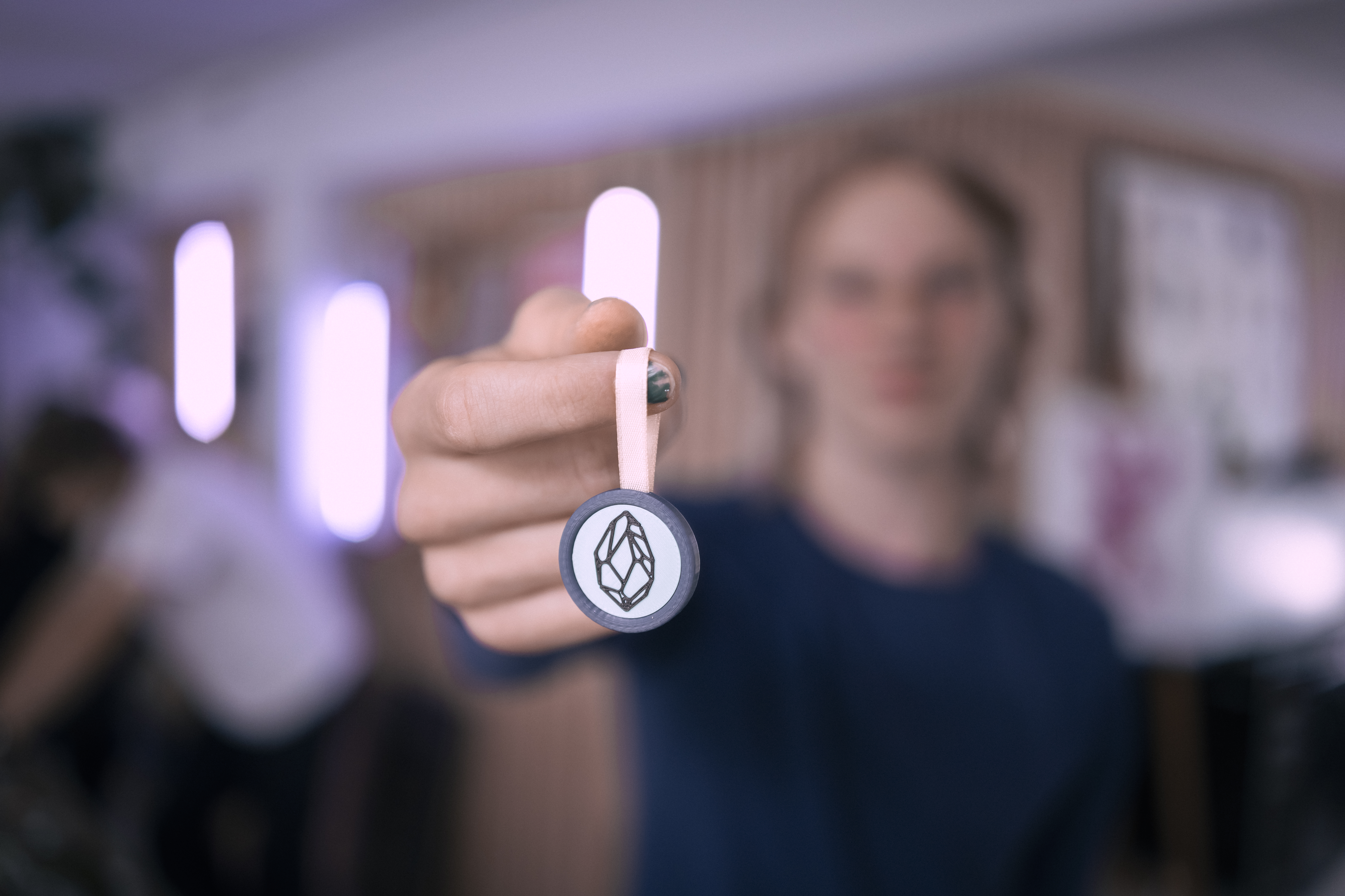 Elev viser en medalje med et geometrisk mønster frem mod kameraet