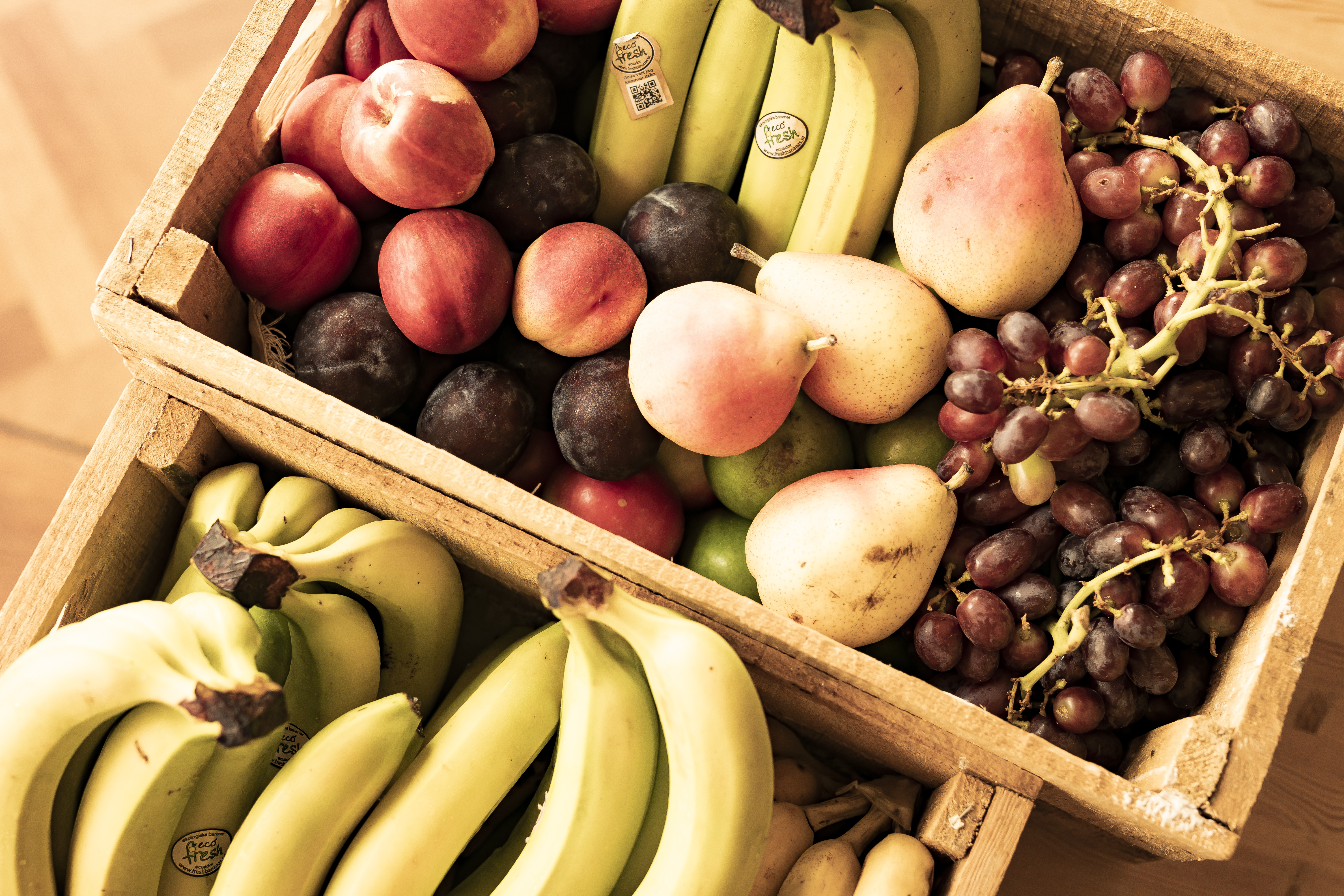 Frugtkasse med bananer, druer, ferskener, pærer og blommer
